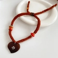 Primer plano de pulsera trenzada marrón con cuentas de madera y colgante de corazón - Estilo Corazón Marrón