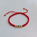 Dettaglio del bracciale in corda rossa intrecciata con ciondolo occhio greco dorato lucido - Stile Malocchio Portafortuna con Filo Rosso