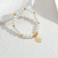 Dettaglio del braccialetto di perle con distanziatori dorati e un piccolo ciondolo a margherita - Distanziatore a margherita con perle