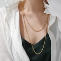 Detail of layered gold snake chain necklace on model with elegant metallic finish - H372 1.2m Round Snake Gold Necklace