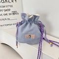Détail du sac à cordon vichy bleu avec écusson de dessin animé et perles colorées - Grille bleue avec pois colorés