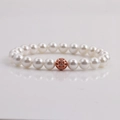 Elegant white pearl bracelet with a rose gold hollow filigree charm on a white surface - White