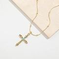 Gold cross necklace with colorful gems and devil eye pendant on stone surface - Colorful