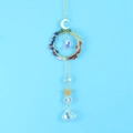 Detail view of gold sun catcher with colorful crystals and moon pendant on blue background - Rainbow