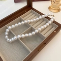 Détail de perles baroques crème avec fermoir doré dans un écrin à bijoux en bois sombre - Collier de perles blanches (env. 14 mm)