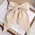 Elegant beige fabric oversized bow hair clip on a vintage decorative display - Beige