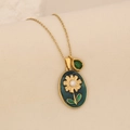 Macro shot of gold floral pendant with green daisy inlay and teardrop gem detail - Green