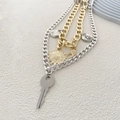 Détail d'un collier hip-hop multicouche avec pendentifs clé, tournesol et lune stylisés - Or et Argent