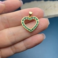 Vue macro d'un pendentif cœur doré serti de pierres précieuses carrées vertes - Vert