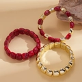 Detail von roten Harzperlen und goldenen Metallkugeln im 3-teiligen dehnbaren Armband-Set - Rosarot