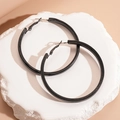 Close-up of black geometric hoop earrings on a textured stone base with soft lighting - 7cm Hoop / Black (7cm)