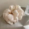 Dettaglio del fermaglio per capelli in raso crema con perle su un vassoio metallico - Molletta con Perle Color Champagne