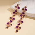 Détail macro de boucles d'oreilles fleurs mauves avec chaîne dorée et cristaux sur marbre - Silver Earring Post - Violet