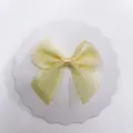 Close-up of a light yellow polka dot organza bow hair accessory on white cardstock - 300pcs / Beige