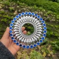 Macro shot of silver circular metal wall decor with radial pattern and blue eye stones - Bright Silver Dark Blue