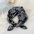 Elegant paisley square scarf in black and white tied on cream fabric backdrop - Flower Vine Black