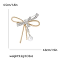 Elegante spilla a fiocco dorata con strass scintillanti e ciondolo con perla bianca - Oro/Argento