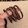 Five pieces of elastic leopard print hair ties with matte brown connectors shown on hand - Leopard Double Strand