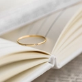Minimalist gold titanium steel ring with fine zircon on an open book background - Ultra-thin Single Stone