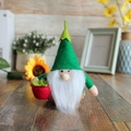 Handmade gnome plush with green leaf hat and red fruit in a cozy rustic home setting - Green Hat Tomato