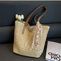 Detail der gewebten Strohtasche mit braunen PU-Riemen und Tulpen auf einem Ledersofa - Weiß