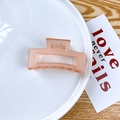 Matte dusty pink square hair claw clip with rectangular cutout design on a ceramic plate - Jelly Orange