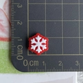 Detailed close-up of a 1.2cm mini red and white snowflake resin charm on a scale mat - 02-Red with White Snowflake