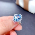 Elegant silver ring with a large oval blue topaz stone and sparkling halo of white gems - Adjustable Open / Silver Tone Topaz Blue