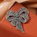 Broche nœud vintage argentée avec pierres noires micro-pavées sur fond en cuir de luxe - Nœud gris argent