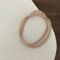 Beigefarbenes elastisches Haargummi mit drei Lagen und goldenen Perlen auf Sockel - Dreisträngig Goldperle / Khaki