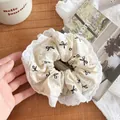 Chouchou beige avec motif nœud noir et bordure en dentelle blanche sur bois - Chouchou dentelle beige / Poche zippée