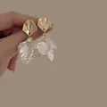 Elegant gold flower earrings with white shell petals and crystal accents on model - Petal Flower Earrings