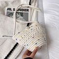 Close-up of woven straw bucket bag with colorful pom-poms and large pearl clasp detail - Colored Polka Dots Style / White