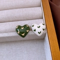 Detailed shot of two heart-shaped enamel earrings in beige jewelry box with wooden frame - Green-White (Enamel Heart)