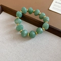 Gros plan d'un bracelet en perles d'acrylique vert jade avec des intercalaires dorés - Bracelet / Vert