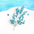 Elegant silver branch brooch with blue marquise cut crystals on a white ceramic plate - Silver Tone + Lake Blue