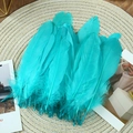 Macro shot of turquoise goose feathers on a woven mat for DIY craft decorations - Stiff Peacock Blue (50Pcs)