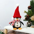 Close-up of plush glowing penguin with knitted hat on wooden stand with Christmas decor - Red Hat Standing Penguin