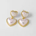 Detalle de aretes de doble corazón dorado con incrustación de perla y borde trenzado - Pendientes colgantes de doble corazón y perla retro
