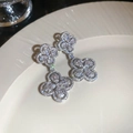 Detailed close-up of clover flower earrings with silver metal and zircon inlay on a ceramic plate - Silver (Silver Pin)