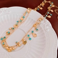 Detail of a double-layered gold necklace with shell charms and turquoise beads on a tray - Gold Double Layer/Shell Pendant
