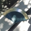 Chinese green and gold folding fan with carved bamboo ribs on a shadow background - Gradient Green
