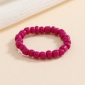 Vista macro di un anello elastico con perline fucsia e perle dalla lucentezza naturale - Rosa Rosso