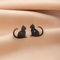 Close-up of minimalist black cat silhouette earrings with hollow heart detail on gold silk - Black