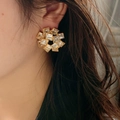 Vintage style gold floral earrings with cubic zirconia crystals worn by a model - White