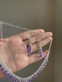 Dettaglio della collana con frange di strass e orecchini a goccia viola tenuti in mano - Collana-Goccia d'Acqua Viola (Set da 2 Pezzi)