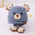 Close-up of blue knit bear ear hat with paw pendant and Kukuji leather label details - 3-8 Years / Blue