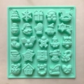 Detailed top view of mint green silicone mold with 25 diverse Christmas themed patterns - Green