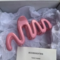 Macro shot of large glossy pink wave hair claw clip inside a white gift box - Pink