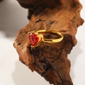 Macro shot of heart-shaped red gemstone ring with 18k gold plating on rustic wood background - Gold Plated Rose Red Zirconia